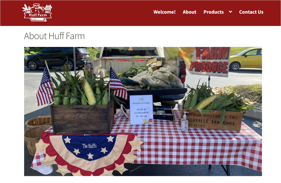 A website with red and white layout. A large image of a picnic table with corn in bins