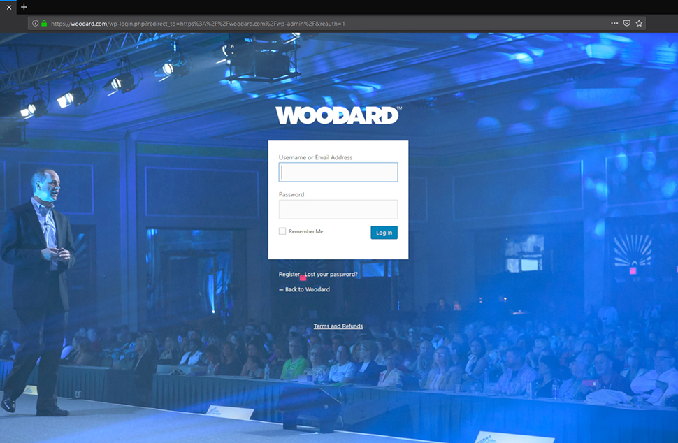 A webpage with a large blue background of a man in a suit on a stage. He looks boring.